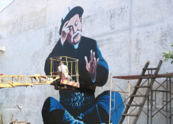 Бишкектеги имаратка манасчы Саякбай Каралаевдин сүрөтү тартылып жатат