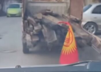 Кыргызстандын желегин унаанын артындагы устунга байлап алган айдоочу кечирим сурады